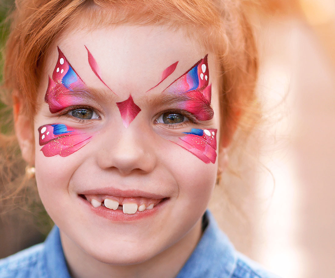 Lächelndes Mädchen mit rotem Haar und pinkem Schmetterling als Kinderschminkmotiv